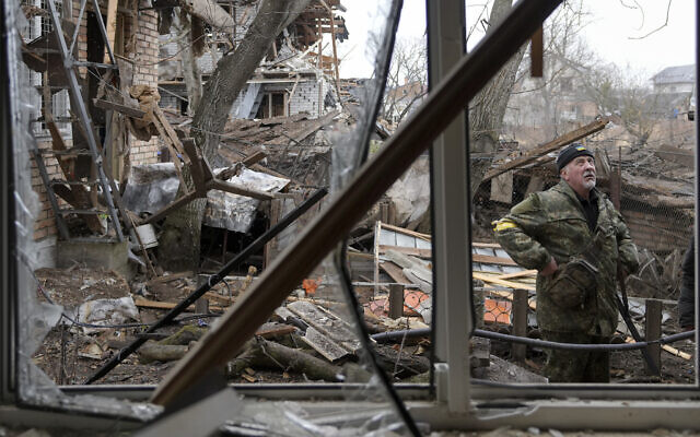 A member of the territorial defense stands in the backyard of a house damaged by a Russian airstrike, according to locals, in Gorenka, outside the capital Kyiv, Ukraine, March 2, 2022. (Vadim Ghirda/AP)
