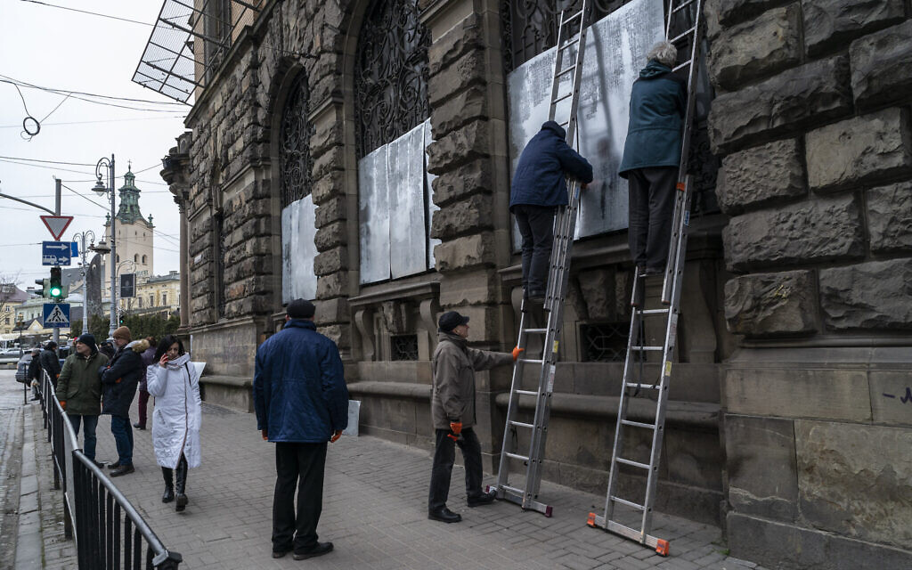 People cover the windows Museum of Ethnography with metal plates in Lviv, western Ukraine, Wednesday, March 2, 2022. (AP/Bernat Armangue)