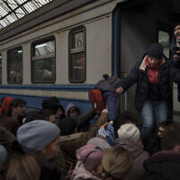 Passengers rush to board a train leaving to Slovakia from the Lviv railway station, in Lviv, west Ukraine, March 2, 2022. (Felipe Dana/AP)