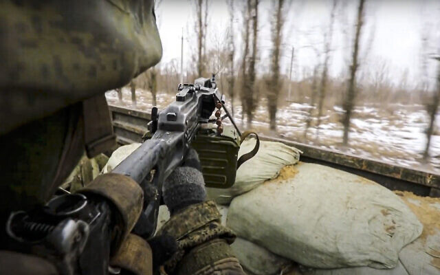 In this photo taken from video released by the Russian Defense Ministry Press Service, on Thursday, March 3, 2022, a Russian soldier points a gun from a Russian military truck as it drives through an undisclosed location in Ukraine. (Russian Defense Ministry Press Service via AP)