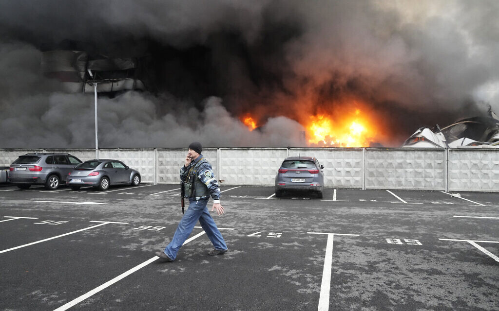A Ukrainian serviceman walks past as fire and smoke rises over a damaged logistic center after shelling in Kyiv, Ukraine, Thursday, March 3, 2022. (AP/Efrem Lukatsky)