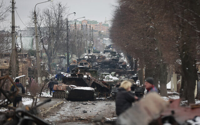 People look at the gutted remains of Russian military vehicles on a road in the town of Bucha, close to the capital Kyiv, Ukraine, on March 1, 2022. (AP Photo/Serhii Nuzhnenko)