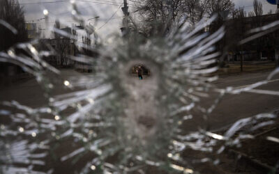 A man is seen through a bullet hole of a machine-gunned bus after an ambush in the city of Kyiv, Ukraine, on March 4, 2022. (AP Photo/Emilio Morenatti)