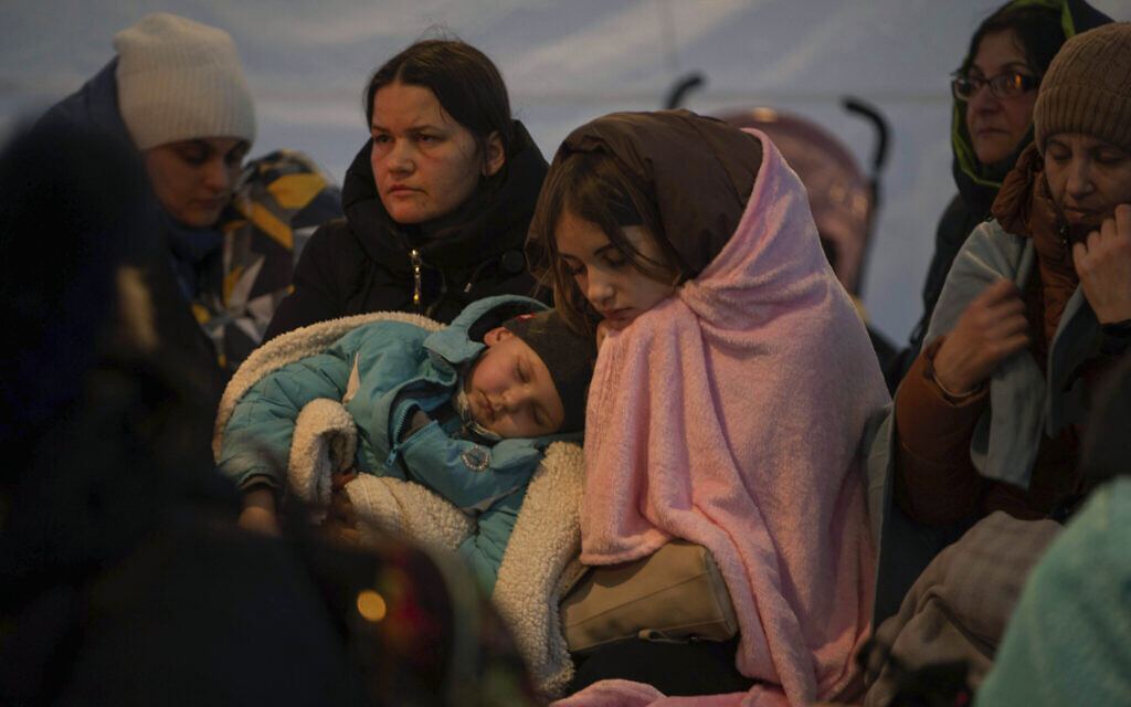 Refugees, mostly women with children, rest inside a tent after arriving at the border crossing, in Medyka, Poland on March 6, 2022. (AP Photo/Visar Kryeziu)