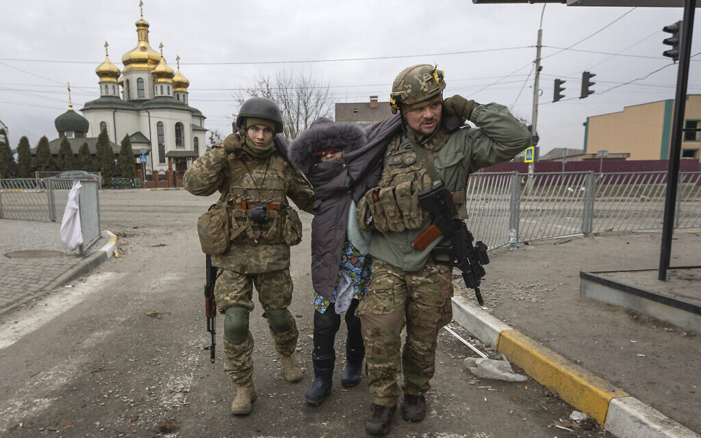 Ukrainian servicemen help an elderly woman, in the town of Irpin, Ukraine, March 6, 2022. (AP Photo/Andriy Dubchak)