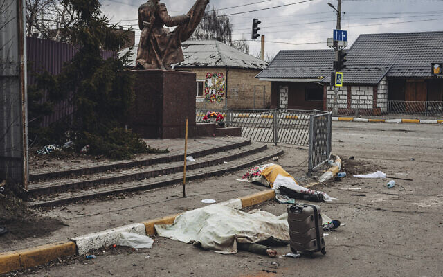 The dead bodies of people killed by Russian shelling lay covered in the street in the town of Irpin, Ukraine, March 6, 2022. (AP Photo/Diego Herrera Carcedo)