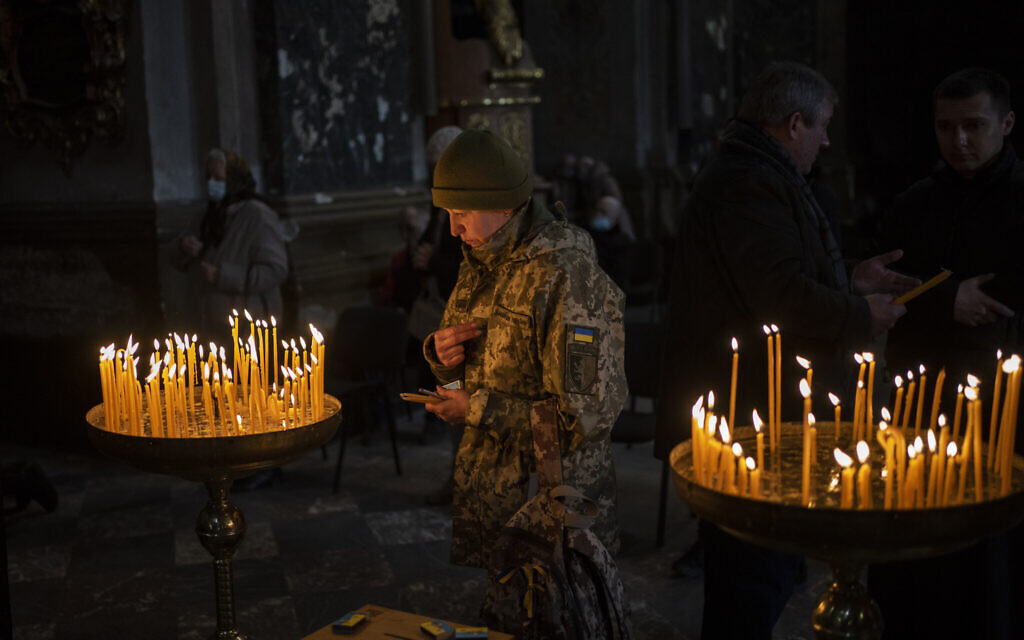 A Ukrainian woman dressed in military attire prays inside the Saints Peter and Paul Garrison Church in Lviv, western Ukraine, March 6, 2022. (AP Photo/Bernat Armangue)
