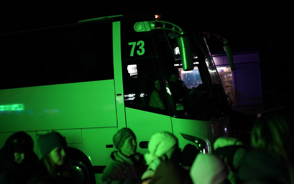A coach driver watches as refugees fleeing the war in Ukraine, form a line as they approach the border with Poland in Shehyni, Ukraine, March 6, 2022. (AP Photo/Daniel Cole)