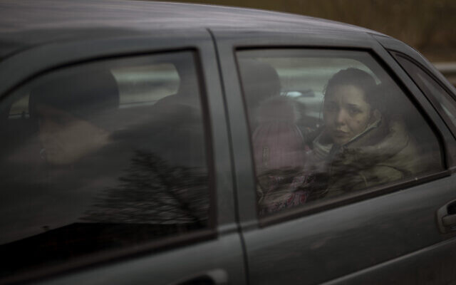 A family flees in a car as Russian troops take positions in Irpin, on the outskirts of Kyiv, Ukraine, March 6, 2022. (AP Photo/Emilio Morenatti)
