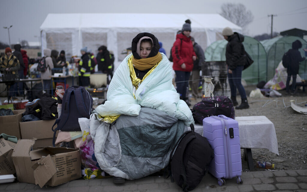 A woman covers herself with a blanket to keep warm after fleeing from the Ukraine and arriving at the border crossing in Medyka, Poland, March 7, 2022. (AP Photo/Markus Schreiber)