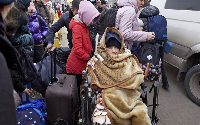 A woman, traveling with others fleeing Ukraine, is wrapped up in a blanket at a border crossing in Palanca, Moldova, March 7, 2022. (AP Photo/Aurel Obreja)