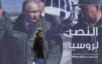 A woman passes a billboard showing Russian President Vladimir Putin in Damascus, Syria, Monday, March 7, 2022. The Arabic reads, "The victory for Russia." (AP Photo/Omar Sanadiki)