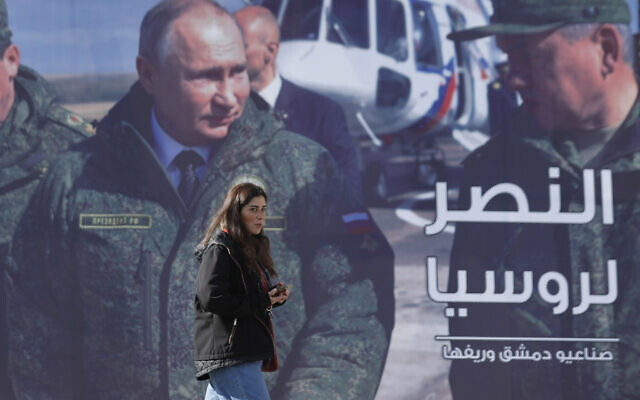 A woman passes a billboard showing Russian President Vladimir Putin in Damascus, Syria, Monday, March 7, 2022. The Arabic reads, "The victory for Russia." (AP Photo/Omar Sanadiki)