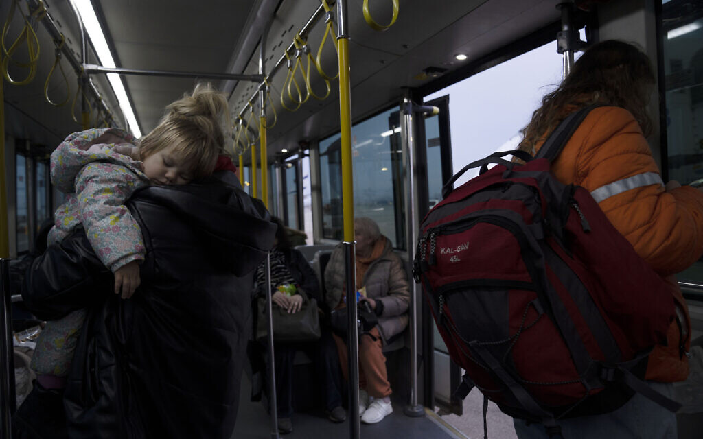A Ukrainian toddler sleeps in her mother's arms on a shuttle bus after a special flight to Israel from Romania upon landing at Ben Gurion Airport, March 8, 2022 (AP Photo/Maya Alleruzzo)