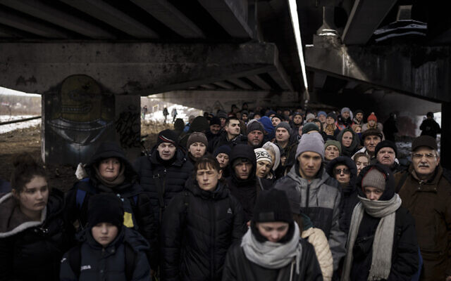 Ukrainians crowd under a destroyed bridge as they try to flee crossing the Irpin river in the outskirts of Kyiv, Ukraine, March 8, 2022. (AP Photo/Felipe Dana)