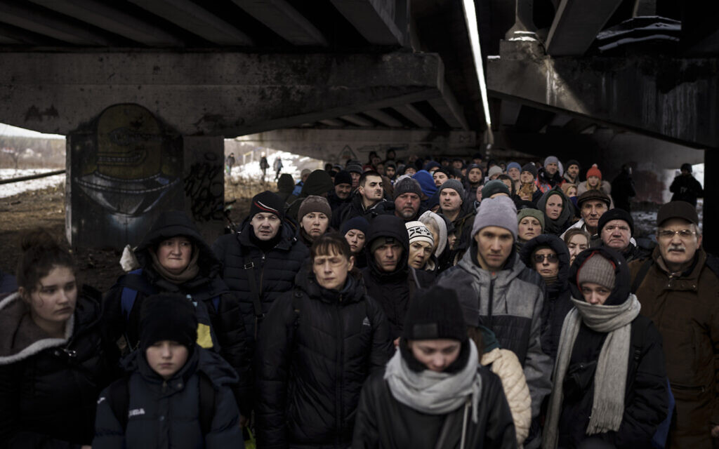 Ukrainians crowd under a destroyed bridge as they try to flee crossing the Irpin river in the outskirts of Kyiv, Ukraine, March 8, 2022. (AP Photo/Felipe Dana)