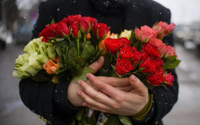 A refugee fleeing the conflict from neighbouring Ukraine holds a bunch of roses, on International Women's Day, at the Romanian-Ukrainian border, in Siret, Romania, Tuesday, March 8, 2022 (AP Photo/Andreea Alexandru)