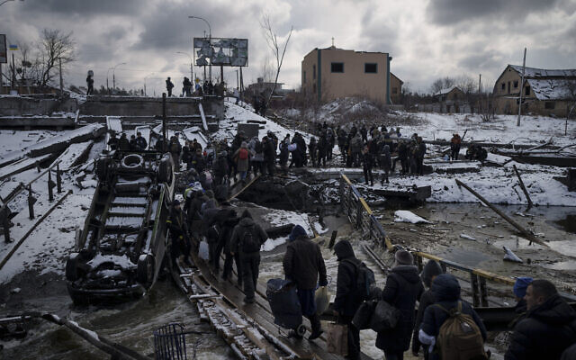 Ukrainians cross an improvised path under a destroyed bridge while fleeing Irpin, in the outskirts of Kyiv, Ukraine, on Tuesday, March 8, 2022. (AP Photo/Felipe Dana)