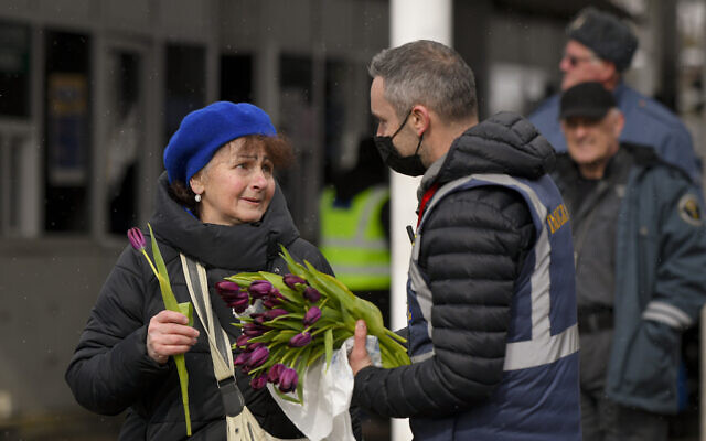 A Romanian Immigrations officer gives flowers to a refugee fleeing the conflict from neighboring Ukraine after she crossed the border on International Women's Day, at the Romanian-Ukrainian border, in Siret, Romania, March 8, 2022. (AP Photo/Andreea Alexandru)