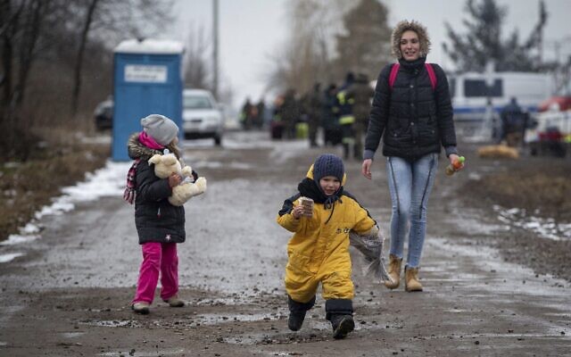 Children, followed by a woman, run as they arrive at the border crossing in Medyka, Poland, after fleeing Ukraine, March 9, 2022 (AP Photo/Visar Kryeziu)