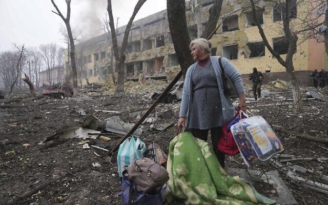 A woman walks outside the damaged by shelling maternity hospital in Mariupol, Ukraine, on Wednesday, March 9, 2022. (AP Photo/Evgeniy Maloletka)