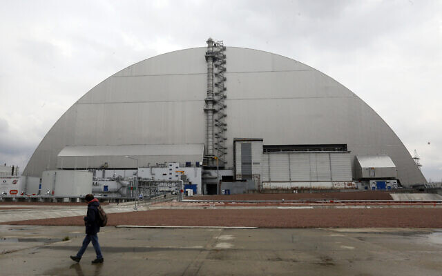 A man walks past a shelter covering the exploded reactor at the Chernobyl nuclear plant, in Chernobyl, Ukraine, on April 15, 2021. (AP Photo/Efrem Lukatsky, File)