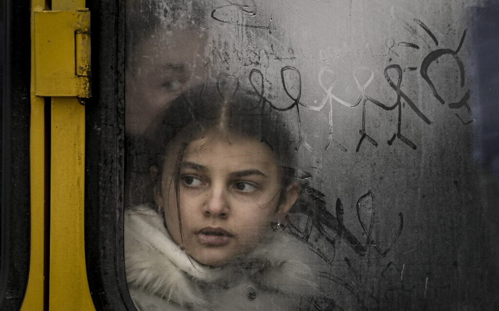 A child looks out a steamy bus window with drawings on it as civilians are evacuated from Irpin, on the outskirts of Kyiv, Ukraine, Wednesday, March 9, 2022 (AP Photo/Vadim Ghirda)