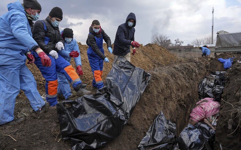 Dead bodies are placed into a mass grave on the outskirts of Mariupol, Ukraine, March 9, 2022, as people cannot bury their dead because of the heavy shelling by Russian forces. (Evgeniy Maloletka/AP)