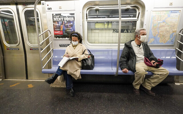 Commuters wear face masks and social distance while riding an M Train, on March 9, 2021, in New York's subway system. (AP Photo/Mary Altaffer, File)