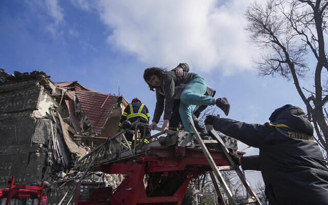 Firefighters help a woman to evacuate from a damaged by shelling apartment building in Mariupol, Ukraine, Thursday, March 10, 2022. (AP Photo/Evgeniy Maloletka)