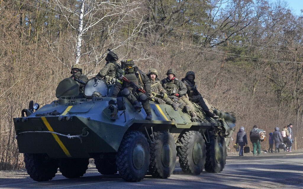 Ukrainian soldiers on an armored personnel carrier pass by people carrying their belongings as they flee the conflict, in the Vyshgorod region close to Kyiv, Ukraine, Thursday, March 10, 2022. (AP/Efrem Lukatsky)