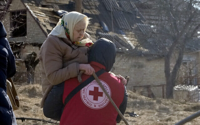 A Red Cross worker carries an elderly women during evacuation in Irpin, some 25 km (16 miles) northwest of Kyiv, March 11, 2022. (AP Photo/Efrem Lukatsky)