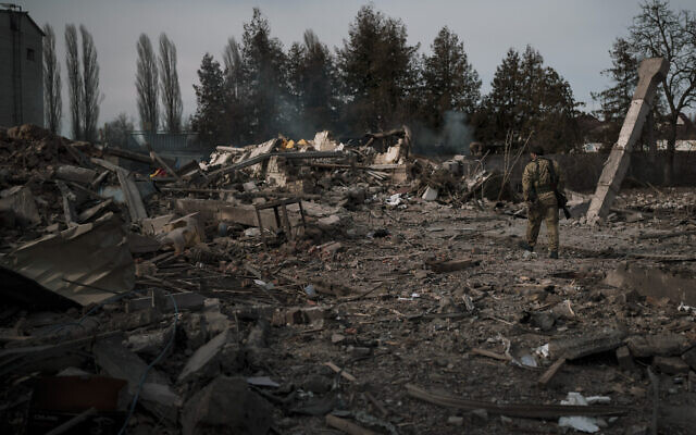 A volunteer of the Ukrainian Territorial Defense Forces walks on the debris of a car wash destroyed by a Russian bombing in Baryshivka, east of Kyiv, Ukraine, March 11, 2022. (AP Photo/Felipe Dana)