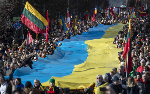People carry a giant Ukrainian flag to protest against the Russian invasion of Ukraine during a celebration of Lithuania's independence in Vilnius, Lithuania, March 11, 2022. (AP Photo/Mindaugas Kulbis)