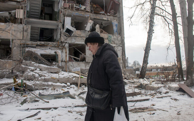 A woman walks past building damaged by shelling, in Kharkiv, Ukraine, March 13, 2022. (AP Photo/Andrew Marienko)