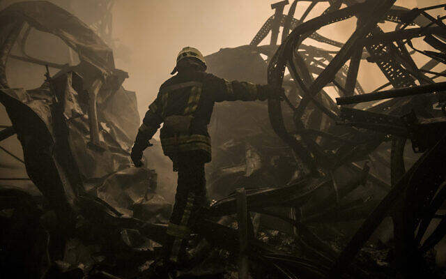 A Ukrainian firefighter walks inside a large food products storage facility which was destroyed by an airstrike in the early morning hours on the outskirts of Kyiv, Ukraine, March 13, 2022. (AP Photo/Vadim Ghirda)