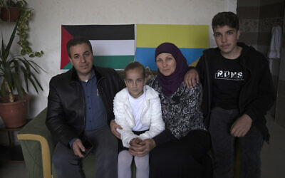 Ukrainian Oksana al-Astal sits with her Palestinian husband and their children as they pose for a photo in front of Palestinian and Ukrainian flags decorating the living room of their home in Khan Younis, southern Gaza Strip, March 13, 2022. (AP Photo/ Khalil Hamra)