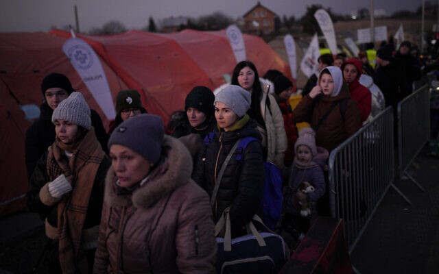 A group of people, who have fled Ukraine, stand in a line after arriving at the border crossing in Medyka, Poland, Sunday, March 13, 2022. (AP/Daniel Cole)