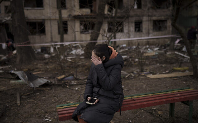 A resident sits outside a destroyed building after it was hit by artillery shelling in Kyiv, Ukraine, Monday, March 14, 2022. (AP Photo/Felipe Dana)
