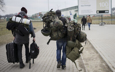 A man carries combat gear as he leaves Poland to fight in Ukraine, at the border crossing in Medyka, Poland, March 2, 2022. (AP Photo/Markus Schreiber)