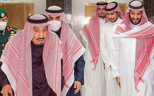 In this photo released by Saudi Press Agency, Saudi King Faisal walks with a cane as he leaves King Faisal Specialist Hospital with Saudi Crown Prince Mohammed bin Salman, right, and entourage, in Riyadh, Saudi Arabia, March, 16, 2022. (Saudi Press Agency via AP)