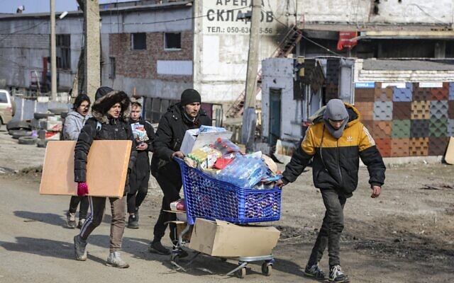 Local residents carry water from the food warehouse, on the territory which is under the Government of the Donetsk People's Republic control, on the outskirts of Mariupol, Ukraine, Friday, March 18, 2022. (AP Photo/Alexei Alexandrov)