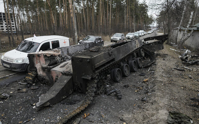 Cars drive past a destroyed Russian tank as a convoy of vehicles evacuating civilians leaves Irpin, on the outskirts of Kyiv, Ukraine, March 9, 2022. (AP Photo/Vadim Ghirda, File)