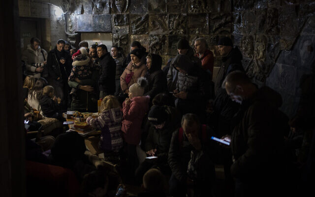 People gather in a basement, used as a bomb shelter, during an air raid in Lviv, Western Ukraine, Saturday, March 19, 2022. Lviv has been a refuge since the war began nearly a month ago, the last outpost before Poland and host to hundreds of thousands of Ukrainians streaming through or staying on. (AP Photo/Bernat Armangue)