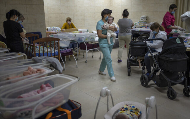 Nannies take care of newborn babies in a basement converted into a nursery in Kyiv, Ukraine, Saturday, March 19, 2022. Nineteen babies were born to surrogate mothers, with their biological parents still outside the country due to the war against Russia. (AP Photo/Rodrigo Abd)