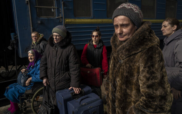 Ukrainians escaping from the besieged city of Mariupol, along with other passengers from Zaporizhzhia, arrive at Lviv, western Ukraine, on March 20, 2022. (AP Photo/Bernat Armangue)