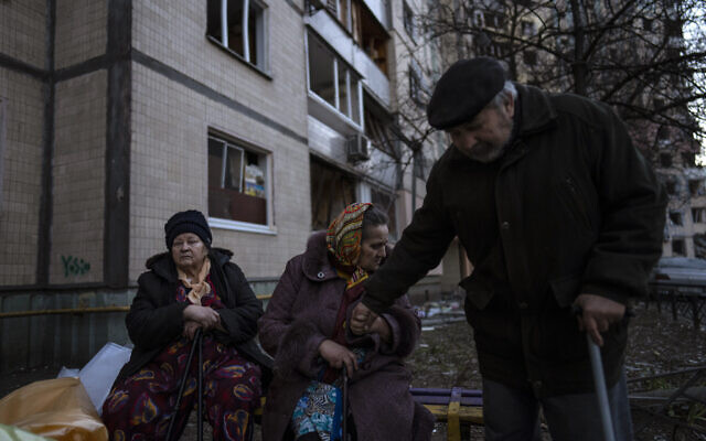 People gather outside their destroyed buildings after a bombing in Satoya neighborhood in Kyiv, Ukraine, March 20, 2022. (AP Photo/Rodrigo Abd)