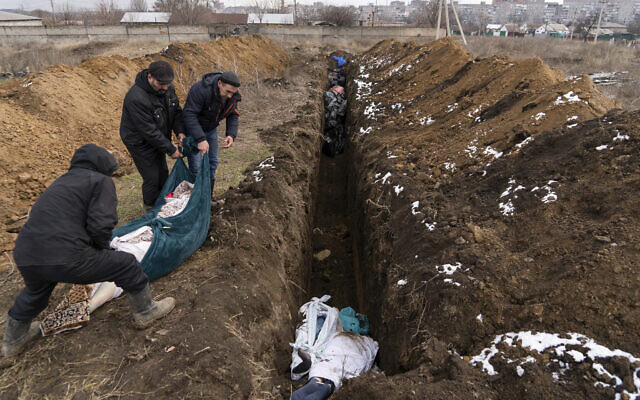 Dead bodies are placed into a mass grave on the outskirts of Mariupol, Ukraine, as people were unable to bury their dead because of heavy shelling by Russian forces, March 9, 2022. (Mstyslav Chernov/AP)