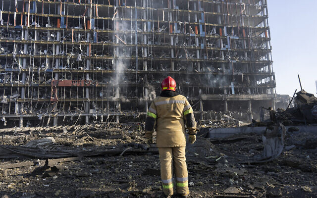 A firefighter looks at the destruction caused after shelling of a shopping center, in Kyiv, Ukraine, March 21, 2022. (AP Photo/Rodrigo Abd)