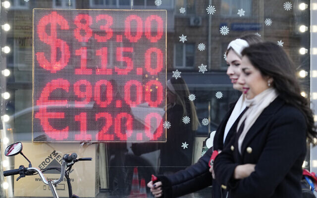 People walk past a currency exchange office screen displaying the exchange rates of US Dollar and Euro to Russian Rubles in Moscow's downtown, February 28, 2022. (AP Photo/Pavel Golovkin, File)
